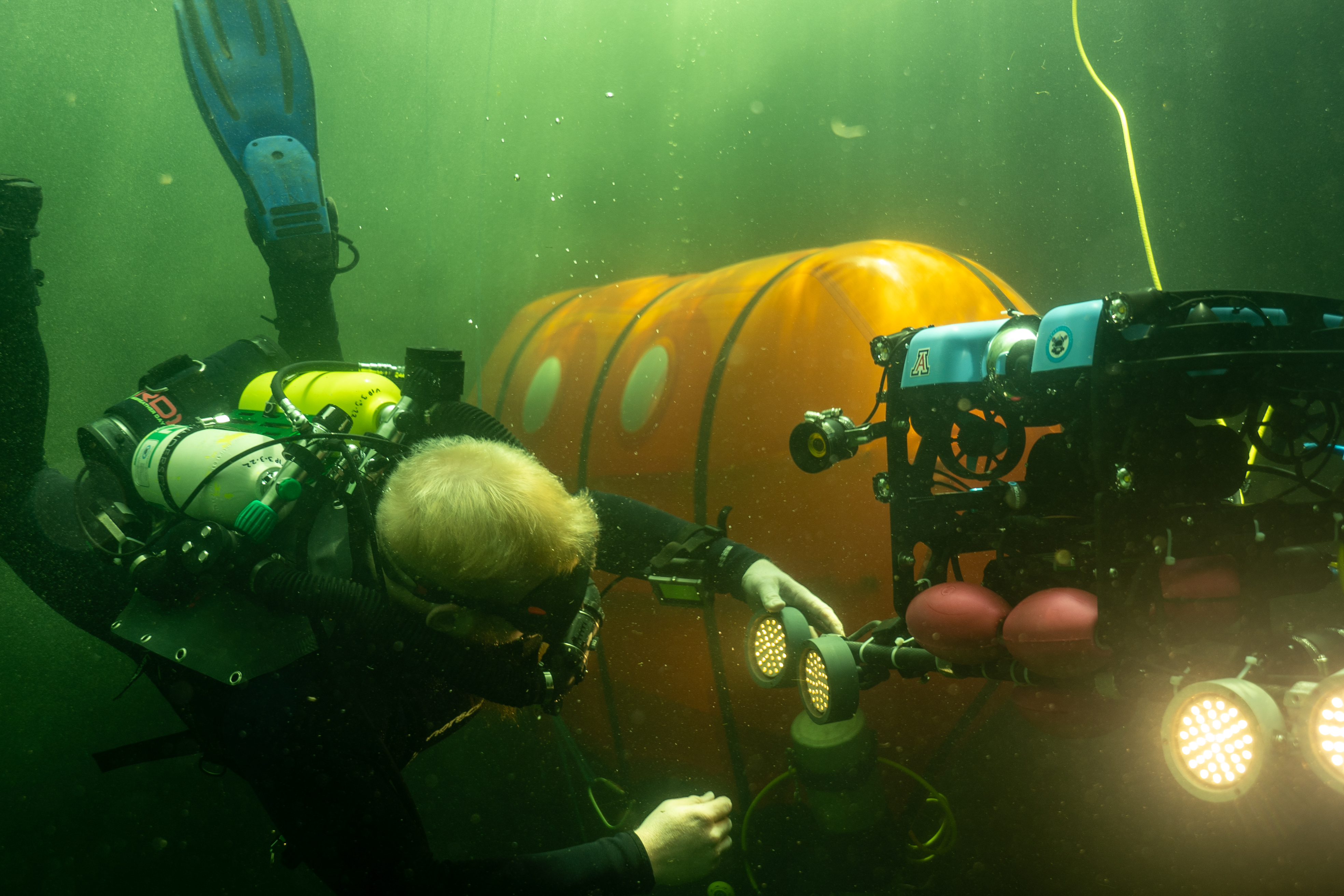 Scientific Diver interacts with robotic vehicle outside of Ocean Space Habitat background