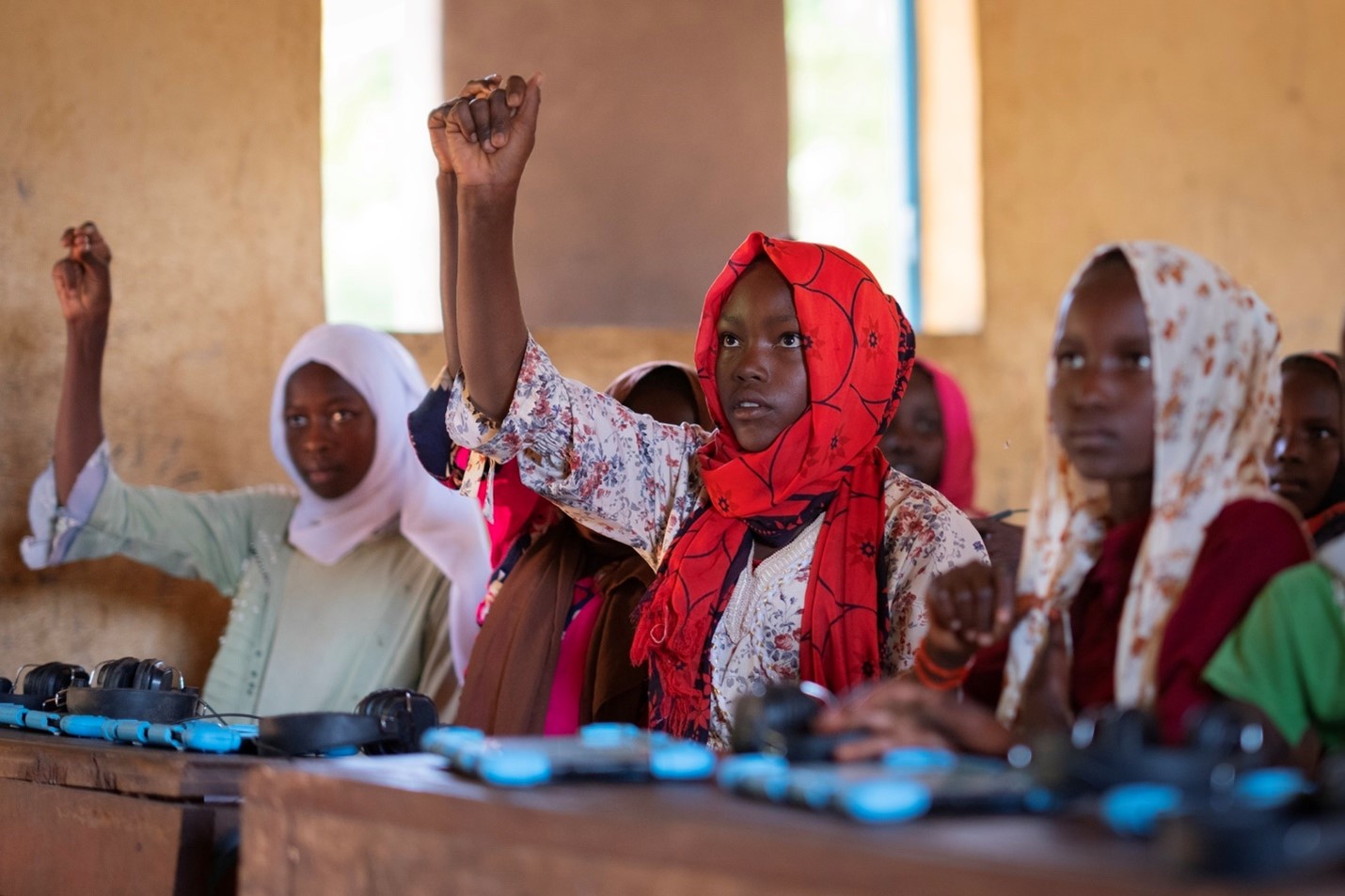 14-year-old student Sumaya Abdel Rahman Mahmoud Mohamad, centre, raises her hand during a lesson, part of an EdTech program developed by War Child named Cant Wait to Learn, at a school in Djabel Refugee Camp, Eastern Chad.